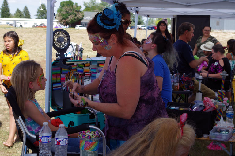 Woman Face painting a child's face during bennett days